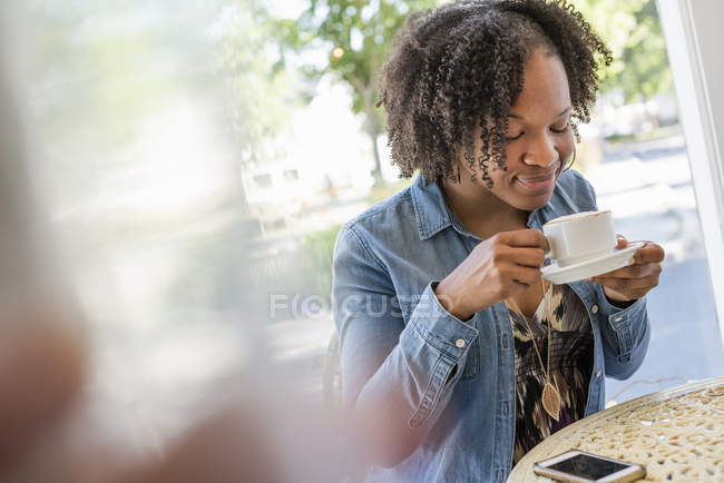 Женщина держит и нюхает кофейную чашку в кафе . — стоковое фото