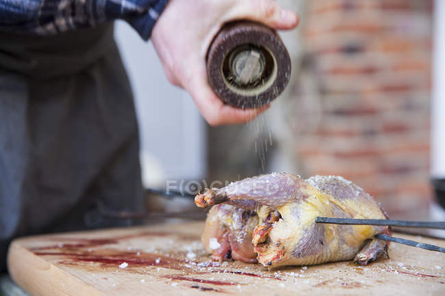 Close-up of man preparing and seasoning game bird for roasting. — Stock Photo