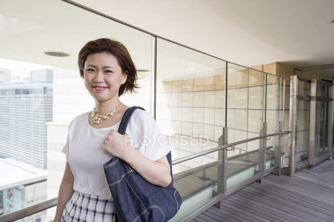 Молодая женщина ходит с сумочкой на дорожке в офисном здании . — стоковое фото