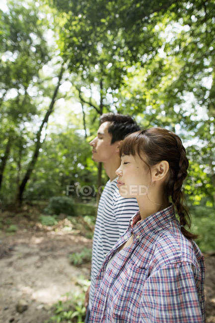 Vista lateral do casal desfrutando de tempo ensolarado na floresta . — Fotografia de Stock