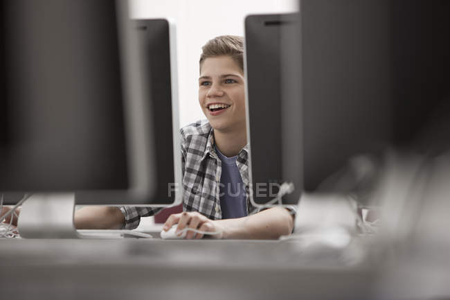Pre-adolescent boy working in computer laboratory with rows of computer monitors. — Stock Photo