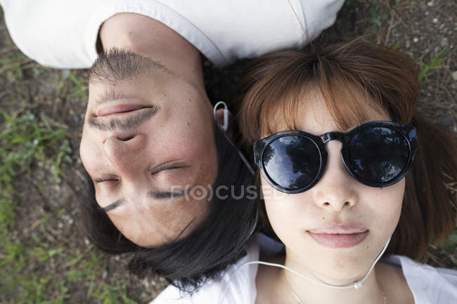 Blick aus der Vogelperspektive auf junge Japaner mit Sonnenbrille am Boden liegend. — Stockfoto