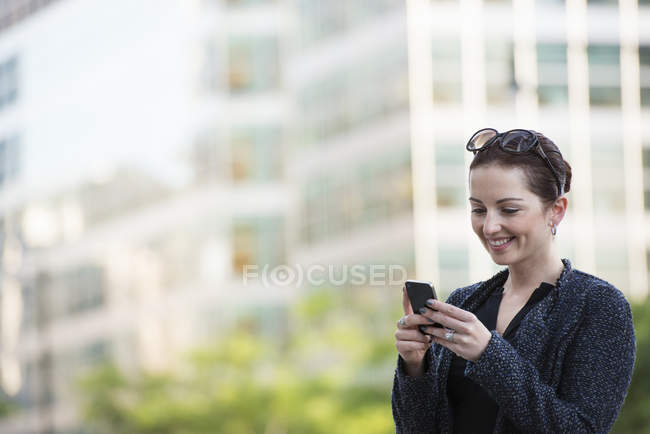 Женщина в серой куртке с помощью смартфона в городе . — стоковое фото