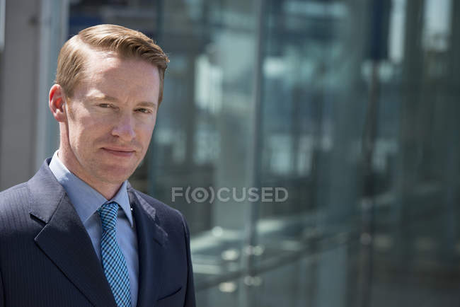 Man in business suit outside building with glass exterior. — Stock Photo