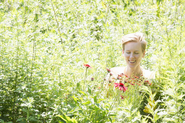 Frau inmitten dichter Blumenwiese bei Gärtnerei. — Stockfoto