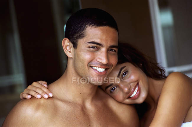 Joven hombre y mujer en topless sonriendo y abrazándose en el interior . - foto de stock