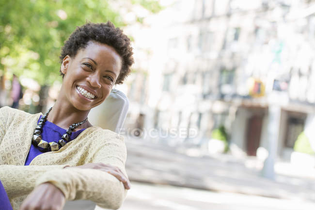 Fröhliche Frau sitzt auf Stuhl im Stadtpark. — Stockfoto