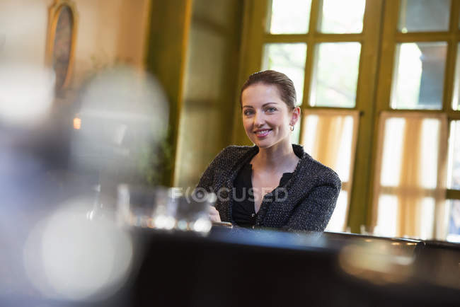 Mujer sentada sola en la mesa en el interior del restaurante y mirando en cámara . - foto de stock