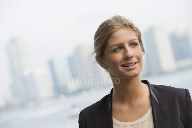 Молода бізнес-леді в чорній куртці дивиться далеко в центрі міста . — стокове фото