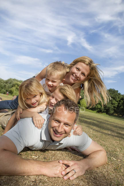 Mid adult couple with children playing in park. — Stock Photo