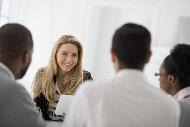 Small group of men and women sitting around table at business meeting in office. — Stock Photo