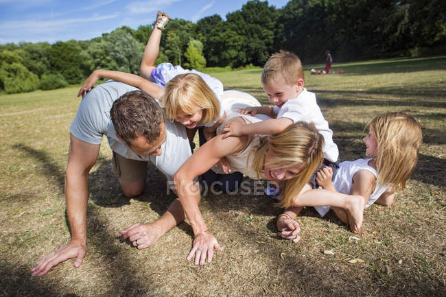 Familie mit drei Kindern spielt im Park. — Stockfoto