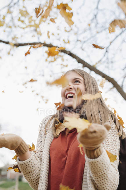 Riéndose adolescente lanzando hojas otoñales en el aire en el parque . - foto de stock