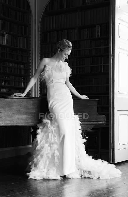 Woman in elegant floor length gown with skirt decorated with feathers. — Stock Photo