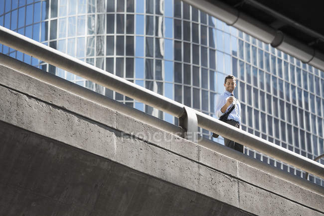 Jeune homme utilisant un téléphone portable sur une passerelle urbaine . — Photo de stock