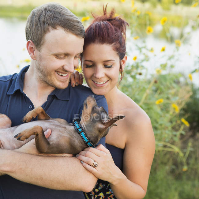 Mid adult couple resting with chihuahua pet dog in park. — Stock Photo
