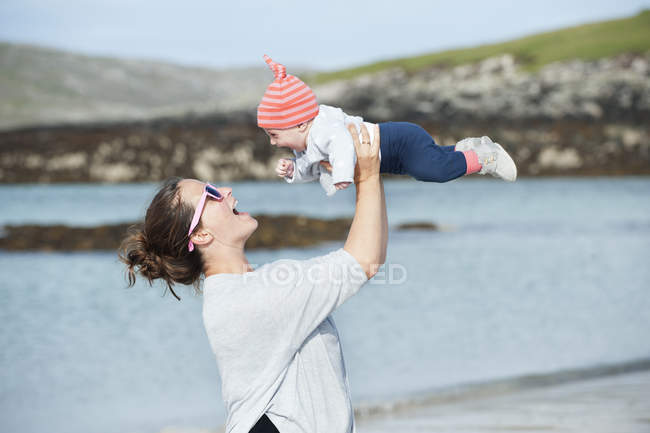 Mamma crescere il bambino a mezz'aria al mare . — Foto stock