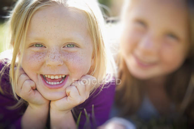 Retrato de dos hermanas rubias de edad elemental sonriendo . - foto de stock