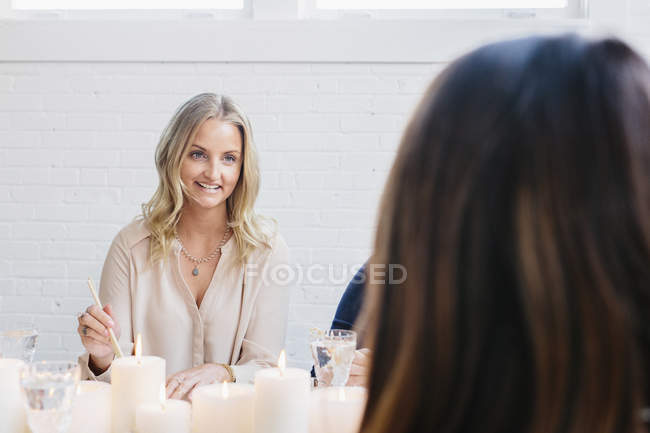 Blondine benutzt Essstäbchen, während sie mit Freunden am Tisch sitzt. — Stockfoto