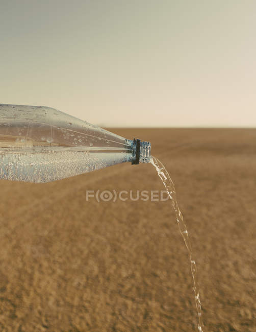 Вода вихлюпується з пляшечки в ландшафті чорний пустелі рок в штаті Невада — стокове фото