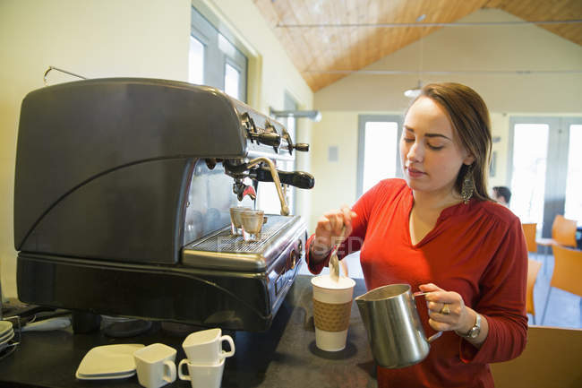 Молода жінка робить каву з використанням великої кавової машини . — стокове фото