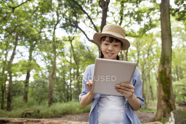 Giovane donna che utilizza tablet digitale nella foresta soleggiata
. — Foto stock
