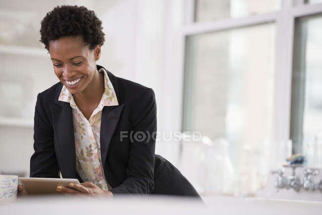 Середня доросла жінка в чорній куртці використовує цифровий планшет в офісі . — стокове фото