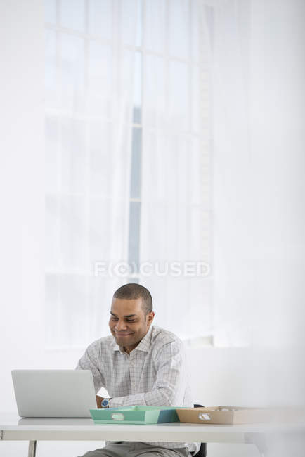 Allegro uomo adulto medio che utilizza il computer portatile alla scrivania dell'ufficio moderno . — Foto stock