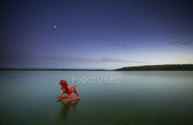 Small red rocking chair on frozen lake surface in Canada. — Stock Photo