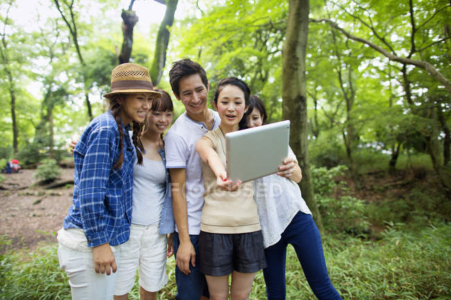 Groupe d'amis asiatiques prenant selfie avec tablette numérique en forêt . — Photo de stock