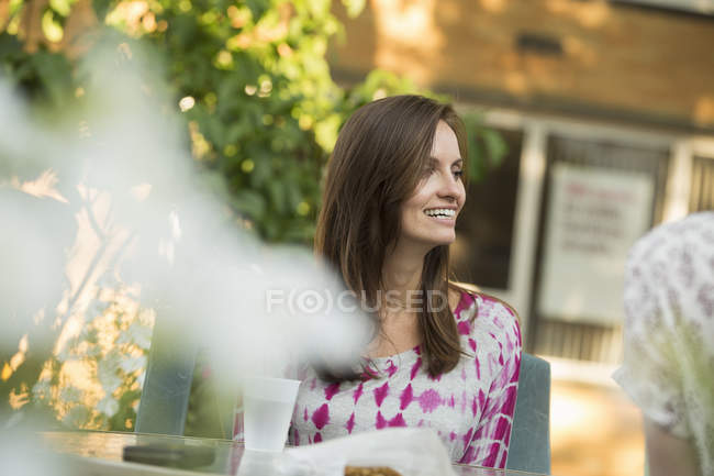 Mujer alegre sentada a la mesa en el jardín . - foto de stock