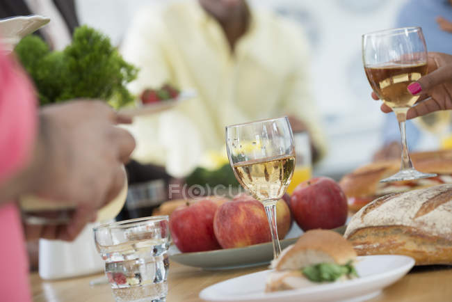 Close-up of hands of people with wine glasses at buffet table at party. — Stock Photo