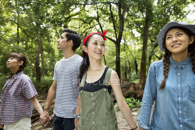 Grupo de amigos andando e de mãos dadas na floresta . — Fotografia de Stock