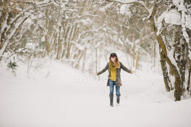 Mitte erwachsene Frau läuft im Schnee im Wald. — Stockfoto
