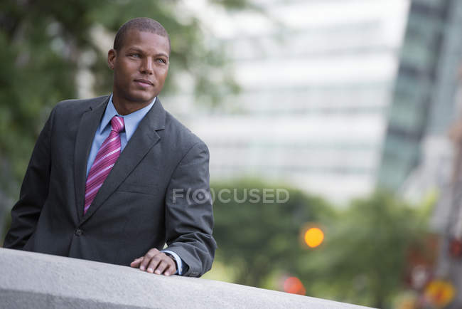 Young businessman in suit standing on city street. — Stock Photo