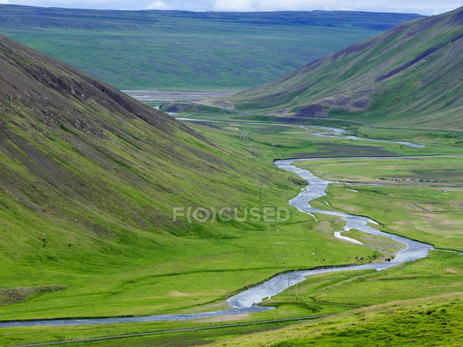 River running through green valley in Iceland mountains. — Stock Photo