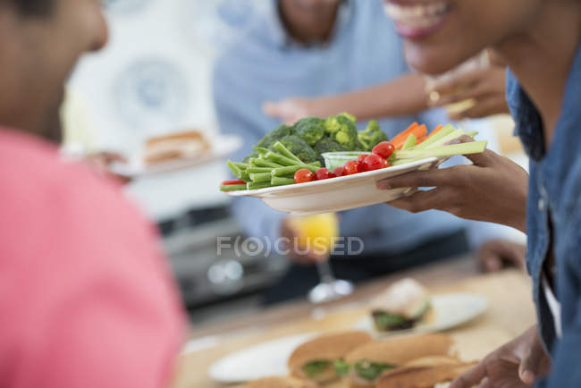 Primer plano de la gente hablando y entregando platos de comida a través de la mesa buffet . - foto de stock