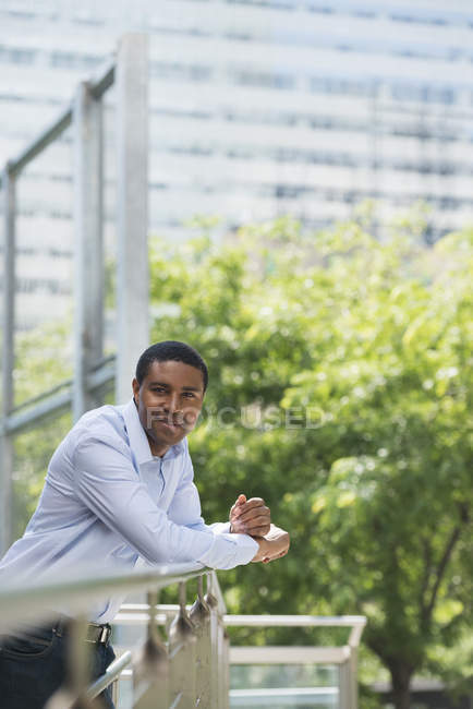 Африканский американец опирается на перила и смотрит в камеру в парке
. — стоковое фото
