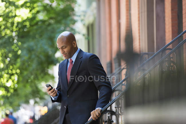 Geschäftsmann im Anzug checkt Telefon auf Baustellen in der Stadt. — Stockfoto