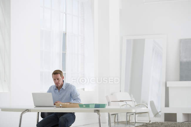 Зрілий чоловік працює з ноутбуком в сучасному офісі . — стокове фото