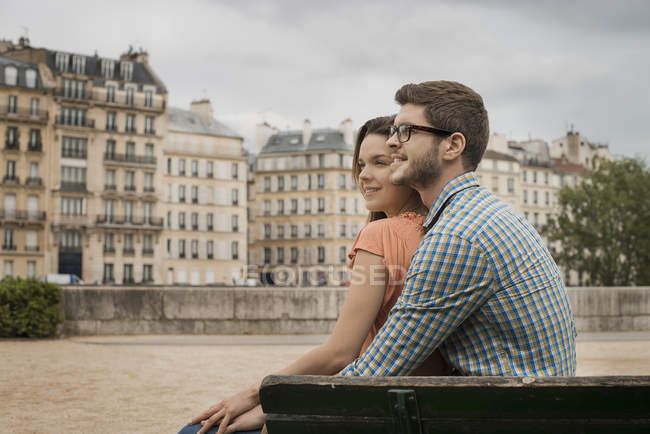 Homem e mulher sentados juntos no banco junto ao Rio Sena em Paris, França . — Fotografia de Stock