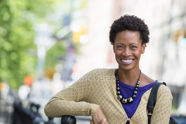Взрослая женщина с короткими волосами, опирающаяся на скамейку, сидя в городе . — стоковое фото