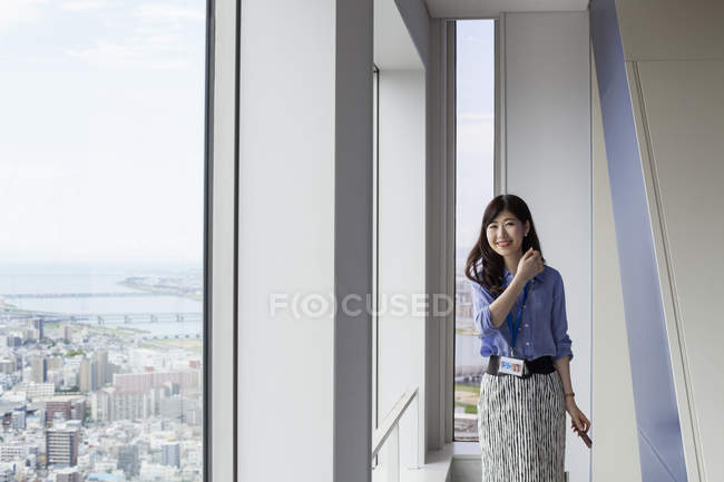 Junge japanische Geschäftsfrau läuft im Flur eines Bürogebäudes. — Stockfoto