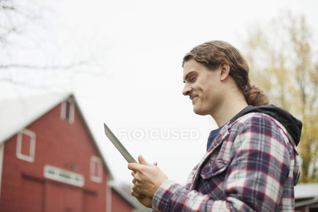 Junger Mann nutzt digitalen Tisch auf Biobauernhof. — Stockfoto