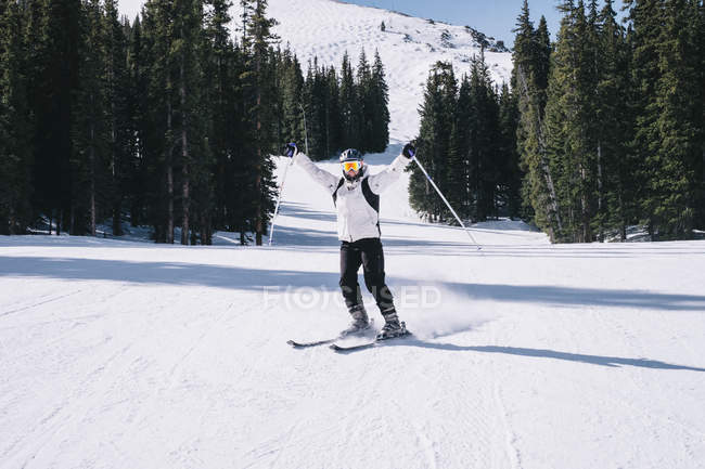 Female skier on skies with arms outstretched on mountain slope at winter resort. — Stock Photo