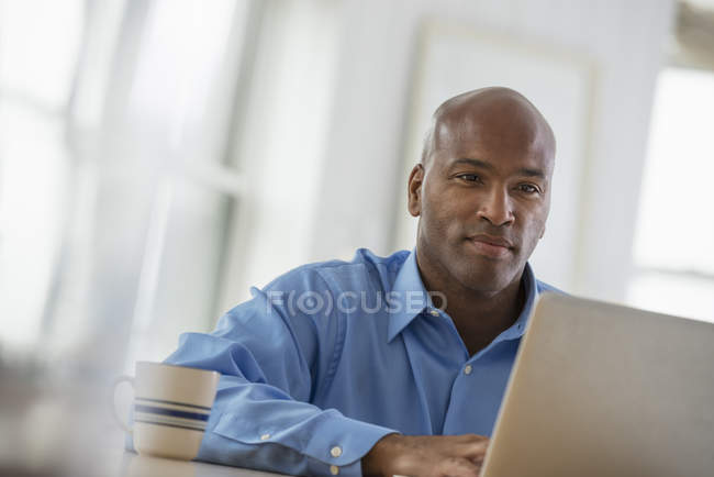 Mitte erwachsener Mann sitzt am Schreibtisch im Büro und benutzt Laptop. — Stockfoto