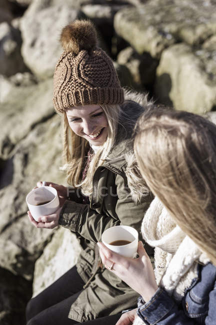 Two young adults having coffee at winter picnic on beach. — Stock Photo