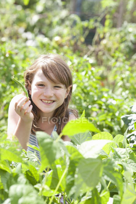 Pre-Teen Mädchen sitzt zwischen frischem grünen Laub des Gartens. — Stockfoto