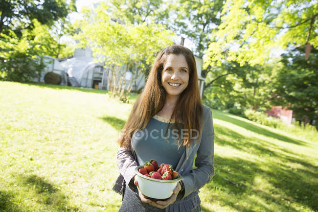 Woman carrying bowl of organic fresh strawberries. — Stock Photo