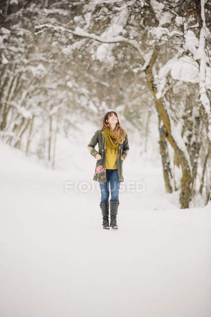 Mid adult woman walking in snow in woodland. — Stock Photo